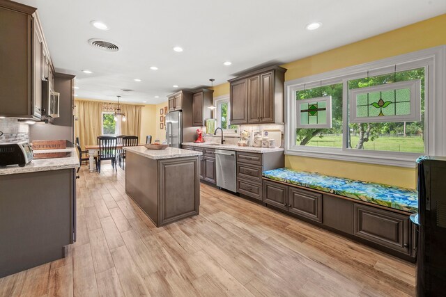 3211 County Road 237, Alvin, TX 77511 - kitchen featuring appliances with stainless steel finishes, a kitchen island, light wood finished floors, pendant lighting, and dark brown cabinets
