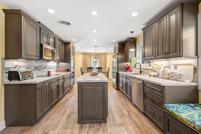3211 County Road 237, Alvin, TX 77511 - kitchen with appliances with stainless steel finishes, a kitchen island, tasteful backsplash, decorative light fixtures, and light wood-style floors