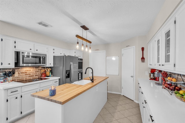 3302 Candlelon Dr, Spring, TX 77388 - kitchen with appliances with stainless steel finishes, white cabinetry, decorative backsplash, a kitchen island with sink, and light tile patterned floors