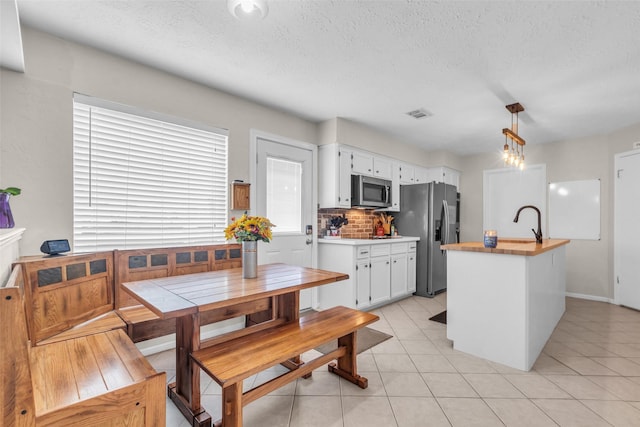3302 Candlelon Dr, Spring, TX 77388 - kitchen with appliances with stainless steel finishes, white cabinets, tasteful backsplash, light tile patterned floors, and a textured ceiling