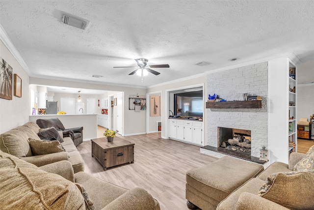 3302 Candlelon Dr, Spring, TX 77388 - living room with crown molding, a textured ceiling, ceiling fan, light wood-type flooring, and a fireplace