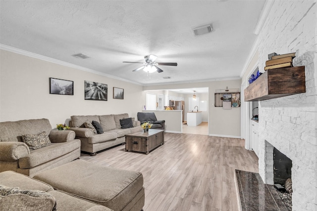 3302 Candlelon Dr, Spring, TX 77388 - living area with a ceiling fan, light wood-type flooring, crown molding, a fireplace with flush hearth, and a textured ceiling