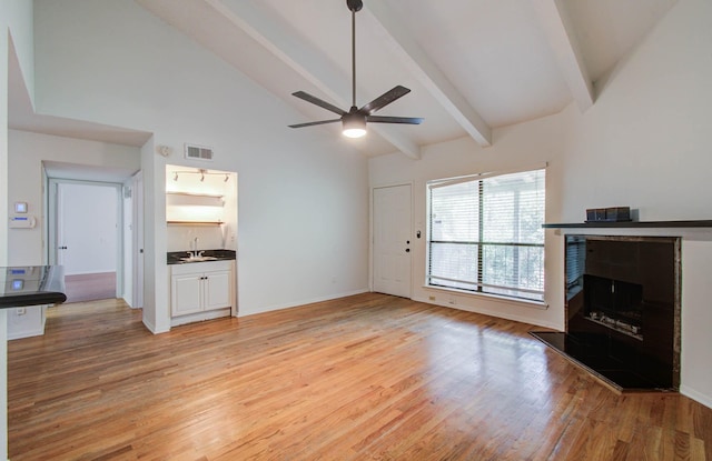 5711 Sugar Hill Dr Unit 108, Houston, TX 77057 - unfurnished living room with a fireplace with raised hearth, ceiling fan, beam ceiling, high vaulted ceiling, and light wood-style floors