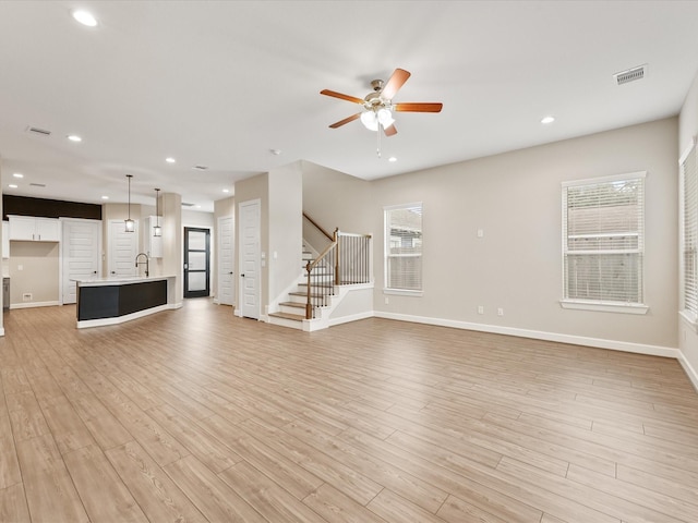 1109 Robbie St, Houston, TX 77009 - unfurnished living room with light wood-type flooring, recessed lighting, ceiling fan, and stairway