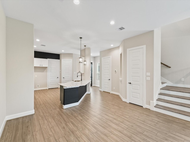 1109 Robbie St, Houston, TX 77009 - kitchen with light wood finished floors, white cabinetry, light stone countertops, a center island with sink, and recessed lighting