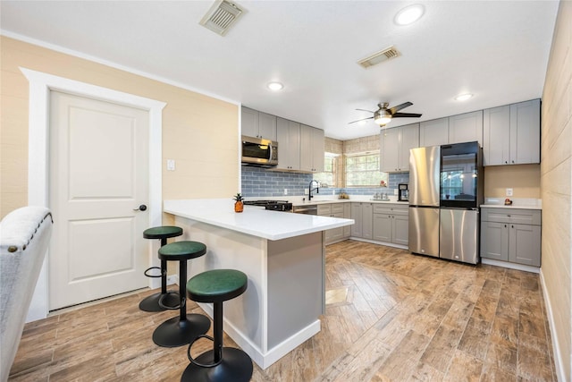 478 Brandon Rd, Conroe, TX 77302 - kitchen with stainless steel appliances, gray cabinetry, a peninsula, a breakfast bar area, and ceiling fan