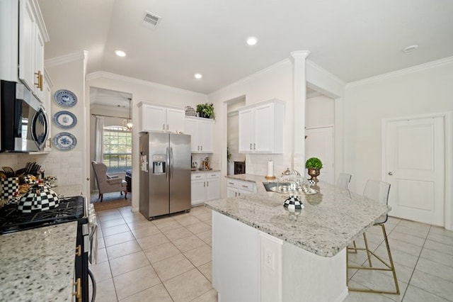 14510 Kasey Flowers Ct, Humble, TX 77396 - kitchen featuring stainless steel appliances, a kitchen breakfast bar, light tile patterned flooring, a peninsula, and ornamental molding
