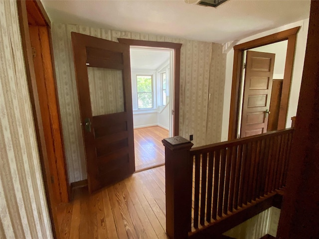 222 N 1st, Wallis, TX 77485 - hall featuring wallpapered walls, light wood-style flooring, and an upstairs landing