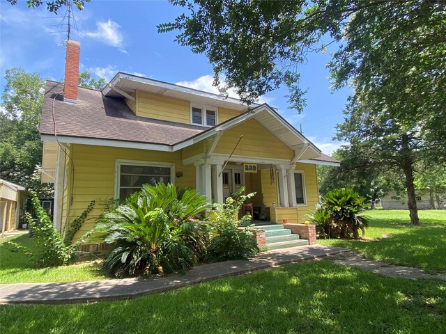 222 N 1st, Wallis, TX 77485 - bungalow-style house with a front lawn, a chimney, a shingled roof, and a porch