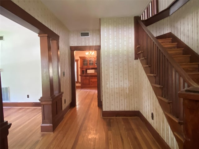 222 N 1st, Wallis, TX 77485 - stairway with wallpapered walls, wood finished floors, and a chandelier