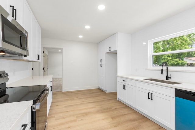 2307 Scott St, La Marque, TX 77568 - kitchen with appliances with stainless steel finishes, light countertops, recessed lighting, white cabinets, and light wood finished floors