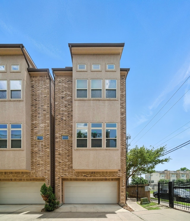 151 E 2nd St, Houston, TX 77007 - view of front of house featuring a garage, concrete driveway, brick siding, and stucco siding