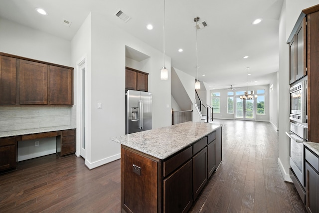 151 E 2nd St, Houston, TX 77007 - kitchen featuring appliances with stainless steel finishes, dark wood finished floors, dark brown cabinetry, a center island, and light stone countertops