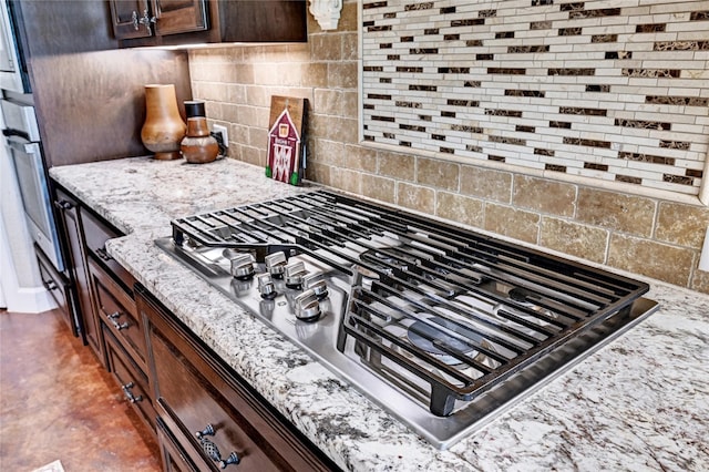 3403 Westhaven Ct, Fulshear, TX 77441 - kitchen view of stainless steel gas stovetop, decorative backsplash, dark brown cabinets, and light stone countertops