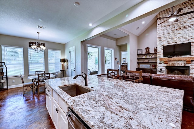 3403 Westhaven Ct, Fulshear, TX 77441 - kitchen featuring light stone counters, a chandelier, white cabinetry, a brick fireplace, and pendant lighting