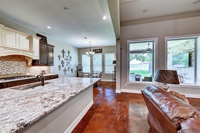 3403 Westhaven Ct, Fulshear, TX 77441 - kitchen with backsplash, concrete flooring, light stone counters, a chandelier, and decorative light fixtures