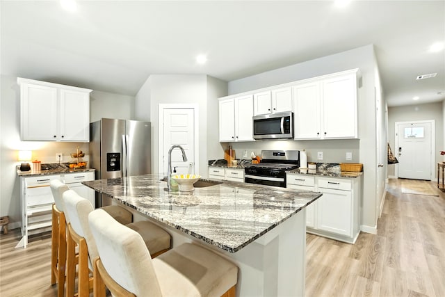 621 Little Spring Ct, Anahuac, TX 77514 - kitchen with stainless steel appliances, light wood-type flooring, a kitchen breakfast bar, light stone counters, and recessed lighting
