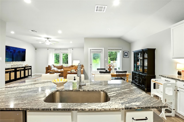 621 Little Spring Ct, Anahuac, TX 77514 - kitchen with dark stone countertops, lofted ceiling, white cabinetry, light wood-style floors, and a ceiling fan