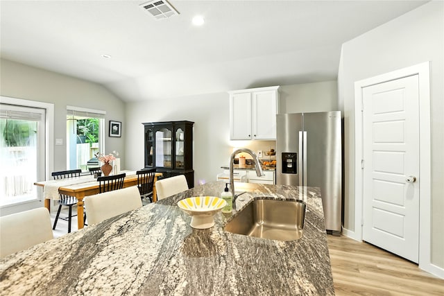 621 Little Spring Ct, Anahuac, TX 77514 - kitchen featuring stainless steel refrigerator with ice dispenser, dark stone counters, light wood-style flooring, white cabinets, and lofted ceiling