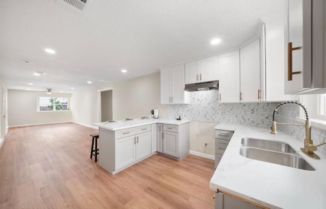 202 Sylvia St, Deer Park, TX 77536 - kitchen featuring under cabinet range hood, a breakfast bar area, open floor plan, recessed lighting, and decorative backsplash