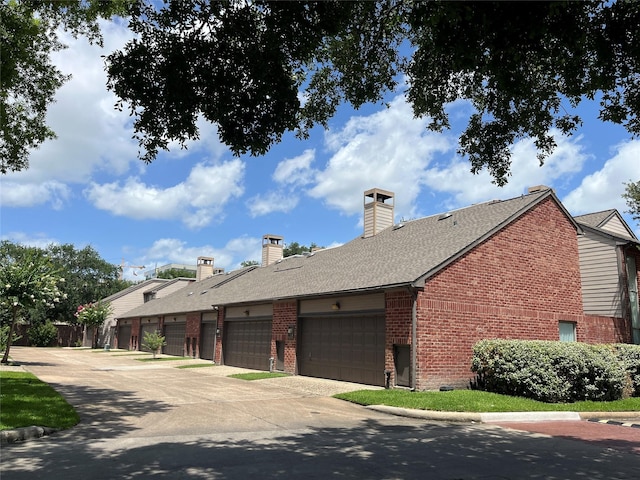7447 Cambridge St Unit 18, Houston, TX 77054 - view of property exterior with brick siding, a chimney, roof with shingles, and concrete driveway