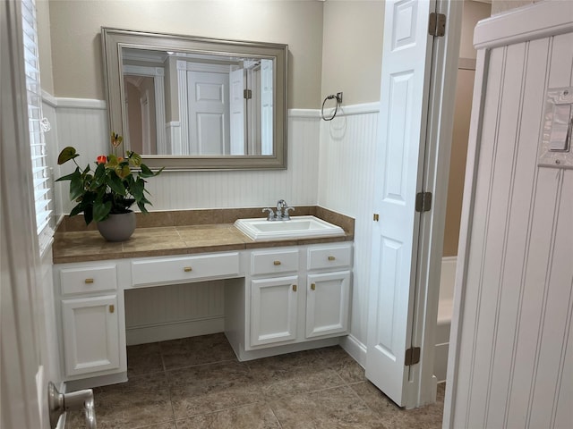7447 Cambridge St Unit 18, Houston, TX 77054 - bathroom featuring vanity, a wainscoted wall, tile patterned floors, and a tub