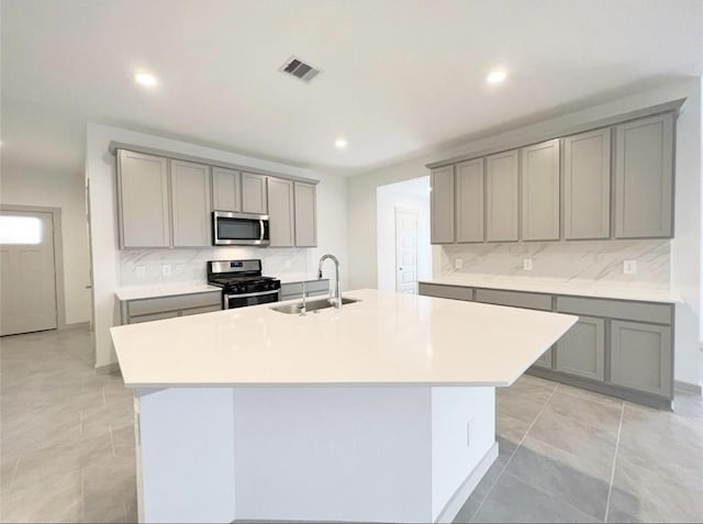 29526 Paytons Park Ln, Katy, TX 77494 - kitchen with stainless steel appliances, gray cabinetry, a kitchen island with sink, tasteful backsplash, and recessed lighting
