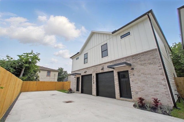 4719 Mallow St, Houston, TX 77033 - view of side of home with board and batten siding, an attached garage, brick siding, and driveway