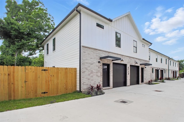 4719 Mallow St, Houston, TX 77033 - view of front facade with brick siding, a garage, driveway, and board and batten siding