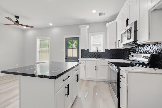 4719 Mallow St, Houston, TX 77033 - kitchen with appliances with stainless steel finishes, light wood finished floors, tasteful backsplash, white cabinetry, and recessed lighting