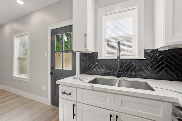 4719 Mallow St, Houston, TX 77033 - kitchen with decorative backsplash, white cabinetry, light stone countertops, and light wood-style floors