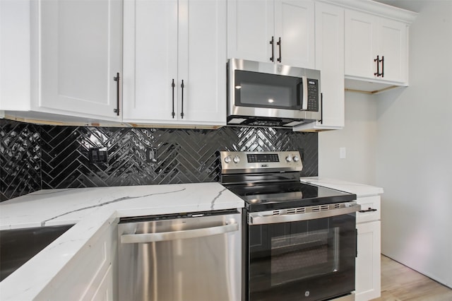 4719 Mallow St, Houston, TX 77033 - kitchen featuring stainless steel appliances, backsplash, white cabinetry, light stone counters, and light wood-style flooring
