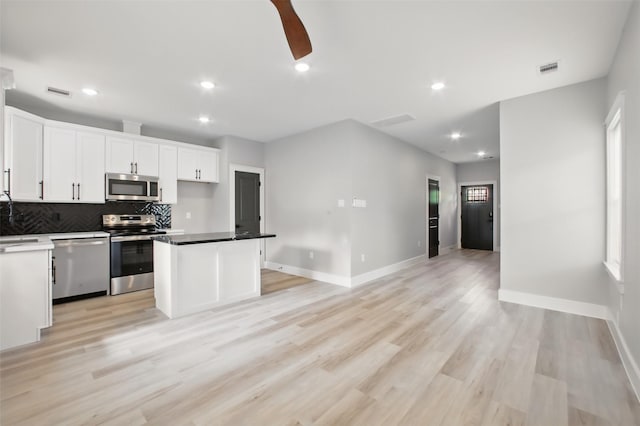 4719 Mallow St, Houston, TX 77033 - kitchen featuring appliances with stainless steel finishes, decorative backsplash, white cabinets, recessed lighting, and light wood-style flooring