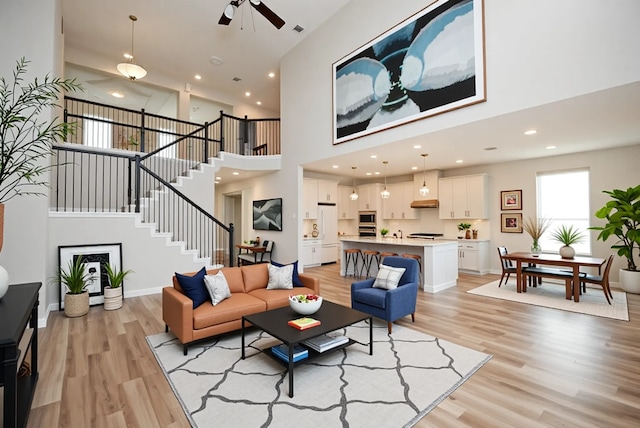4407 Archer Meadow Ln, Sugar Land, TX 77479 - living room featuring light wood-style flooring, ceiling fan, a towering ceiling, stairway, and recessed lighting