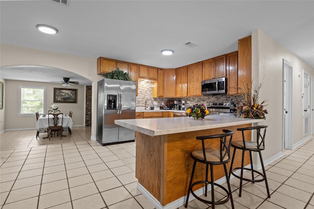 413 Susan St, Lufkin, TX 75901 - kitchen with stainless steel appliances, light tile patterned floors, light countertops, brown cabinetry, and tasteful backsplash
