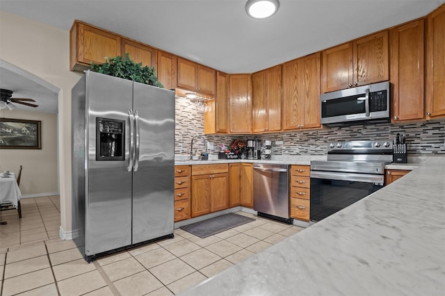 413 Susan St, Lufkin, TX 75901 - kitchen with appliances with stainless steel finishes, light tile patterned floors, light countertops, backsplash, and brown cabinetry