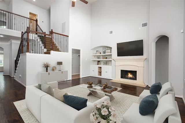 25303 Hall Meadow Ln, Katy, TX 77494 - living area featuring a towering ceiling, dark wood-style flooring, stairway, a fireplace, and a ceiling fan
