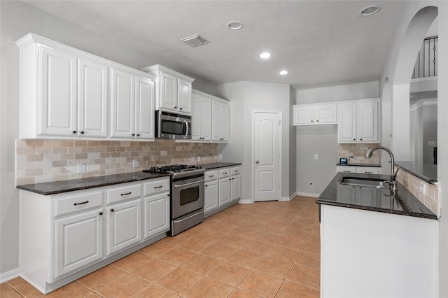 25303 Hall Meadow Ln, Katy, TX 77494 - kitchen with appliances with stainless steel finishes, backsplash, dark stone countertops, white cabinetry, and light tile patterned floors