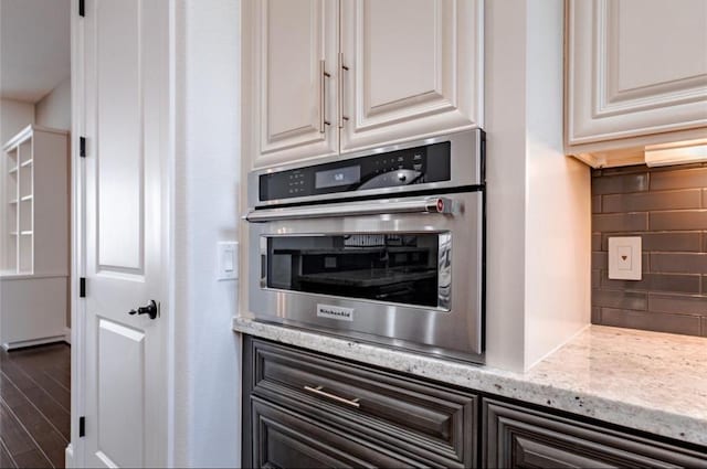 5708 Dolores St Unit A, Houston, TX 77057 - kitchen featuring oven, backsplash, white cabinetry, light stone countertops, and wood finished floors