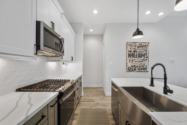 5361 Creekmont Oaks Ln, Houston, TX 77091 - kitchen featuring appliances with stainless steel finishes, light wood-type flooring, tasteful backsplash, hanging light fixtures, and white cabinets