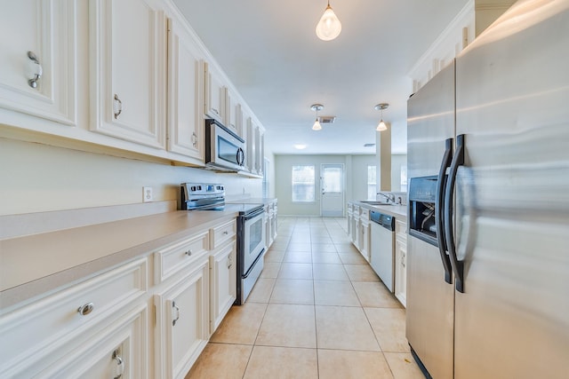 18426 Stark Point Ct, Humble, TX 77346 - kitchen with appliances with stainless steel finishes, light tile patterned flooring, white cabinets, and hanging light fixtures