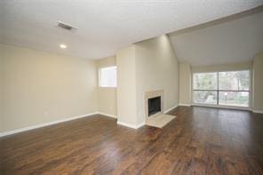 6601 Sands Point Dr Unit 59, Houston, TX 77074 - unfurnished living room featuring wood finished floors, healthy amount of natural light, a fireplace with flush hearth, and recessed lighting