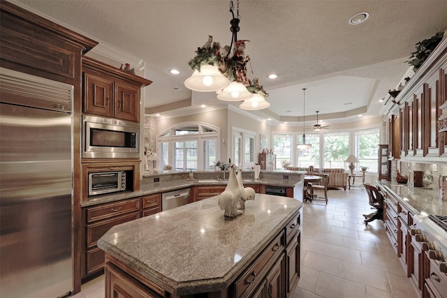 69 W Shore Ln, Montgomery, TX 77356 - kitchen featuring built in appliances, a peninsula, a center island, a tray ceiling, and backsplash