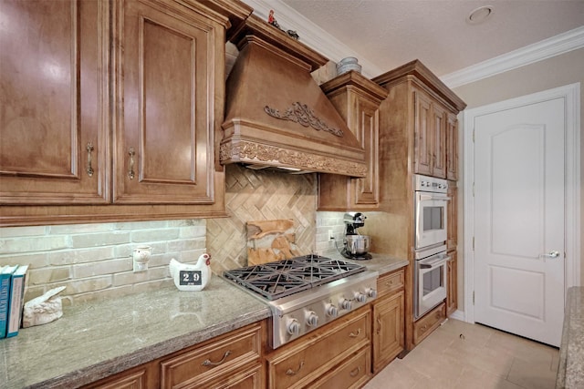 69 W Shore Ln, Montgomery, TX 77356 - kitchen featuring appliances with stainless steel finishes, premium range hood, tasteful backsplash, brown cabinets, and crown molding
