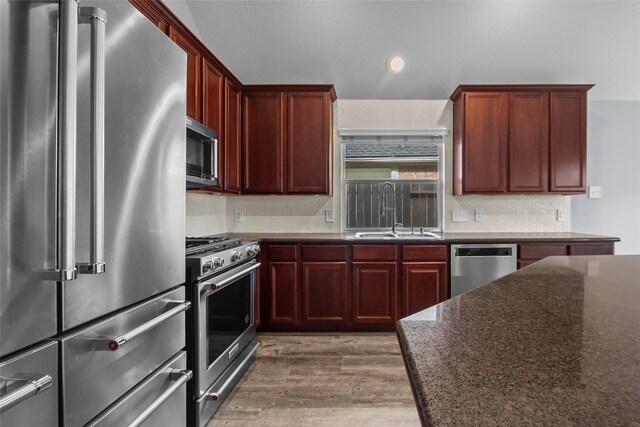 13315 Lake Passage Ln, Houston, TX 77044 - kitchen with premium appliances, dark brown cabinets, wood finished floors, dark stone countertops, and recessed lighting