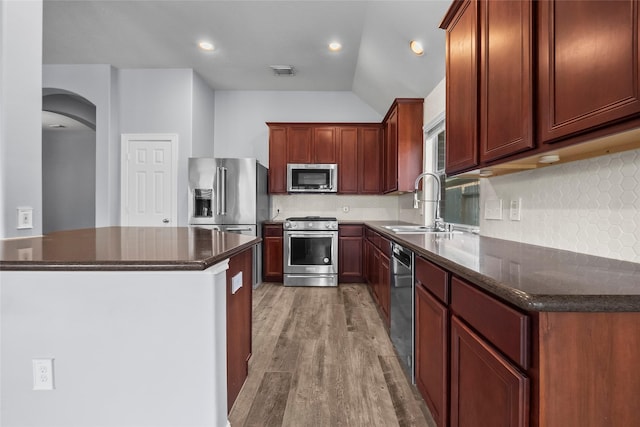 13315 Lake Passage Ln, Houston, TX 77044 - kitchen featuring stainless steel appliances, light wood-style flooring, backsplash, arched walkways, and dark stone countertops