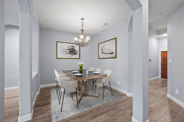 13315 Lake Passage Ln, Houston, TX 77044 - dining room featuring wood finished floors, arched walkways, and a chandelier