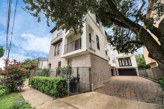 5617 Kiam St Unit A, Houston, TX 77007 - view of property exterior featuring brick siding, an attached garage, stucco siding, a gate, and driveway