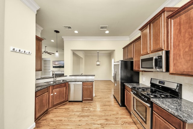 5617 Kiam St Unit A, Houston, TX 77007 - kitchen with appliances with stainless steel finishes, a peninsula, light wood-style floors, dark stone counters, and crown molding
