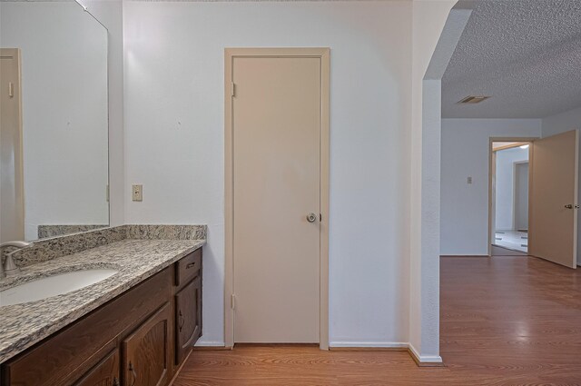 5615 Briarwood Forest Dr, Houston, TX 77088 - bathroom with wood finished floors, vanity, and a textured ceiling
